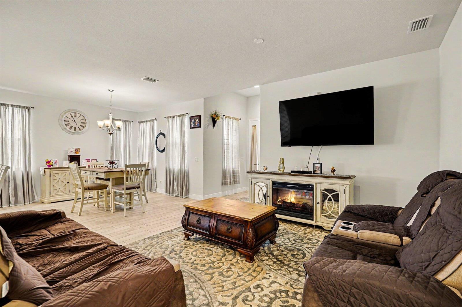 A living room and dining area with tile floors, a fireplace, and brown furniture — 2964 Blazing Star Drive, Melbourne FL 32940, MELBOURNE, FL