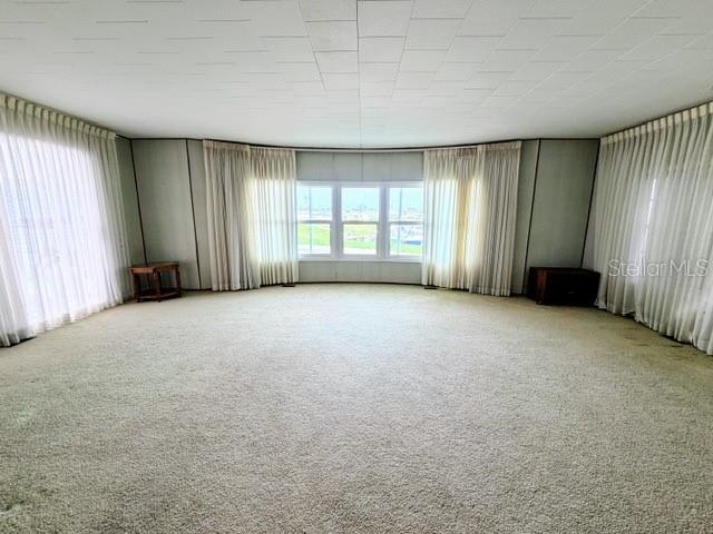 A spacious living room features beige wall-to-wall carpeting, paneled walls, and floor-to-ceiling window curtains — 815 S WATERWAY, VENICE, FL