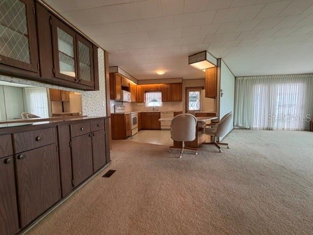 A kitchen with wood cabinets and a carpeted dining area featuring two chairs — 815 S WATERWAY, VENICE, FL