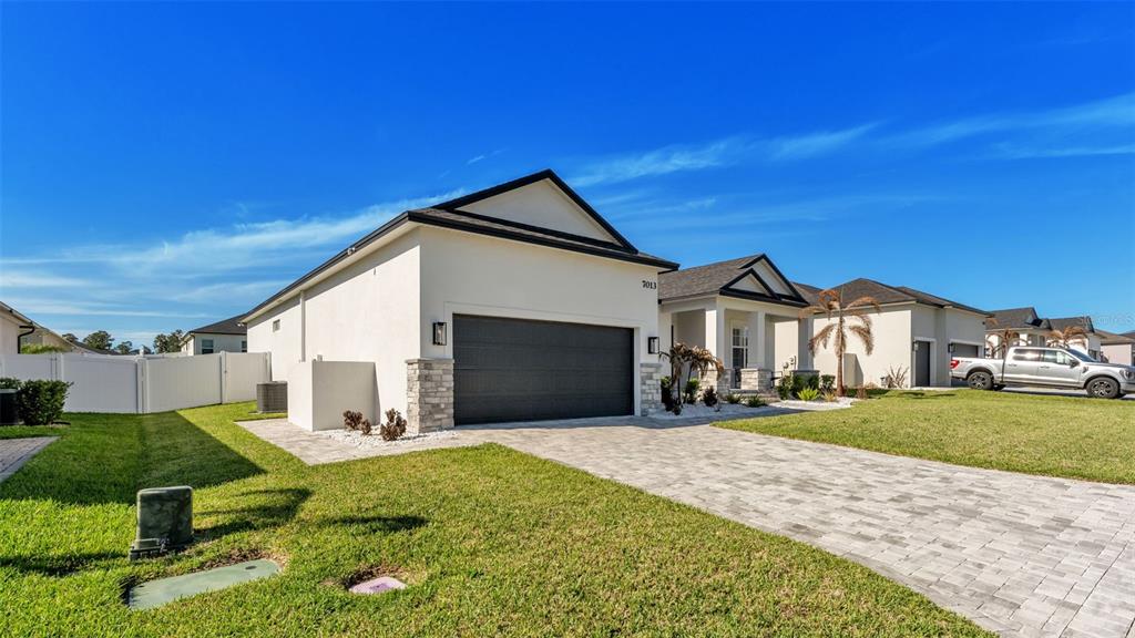 A modern single-story house features a two-car garage, stone accents, and a paved driveway — 7013 BENTRIDGE DRIVE, LAKELAND, FL