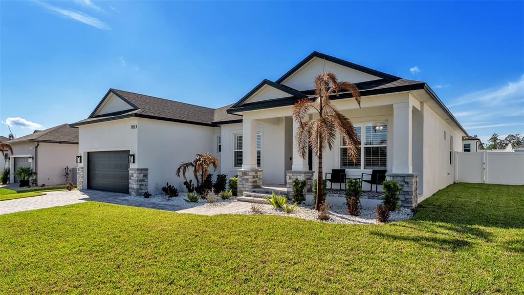A single-story house with a white exterior, dark roof, and a front porch with landscaping — 7013 BENTRIDGE DRIVE, LAKELAND, FL