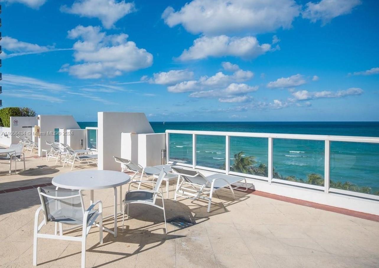 A balcony with outdoor furniture overlooks the ocean under a blue sky — 6365 Collins Ave # 4209, Miami Beach FL 33141, MIAMI BEACH, FL