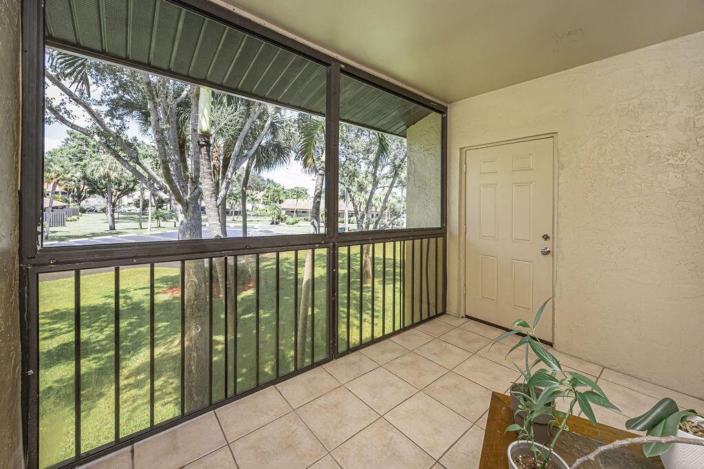 A screened-in porch with tiled flooring, metal railings, and a door leading to the interior — 539 Shady Pine Way # B2, FL 33415, FL