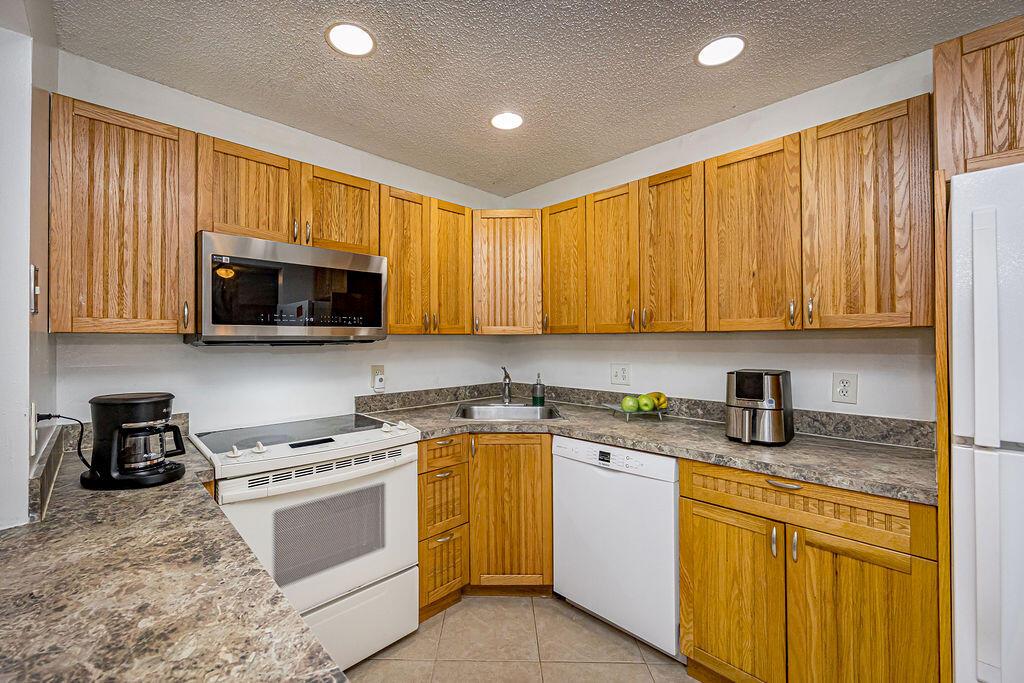 A kitchen with oak cabinets, laminate countertops, white appliances, and tile flooring — 539 Shady Pine Way # B2, FL 33415, FL
