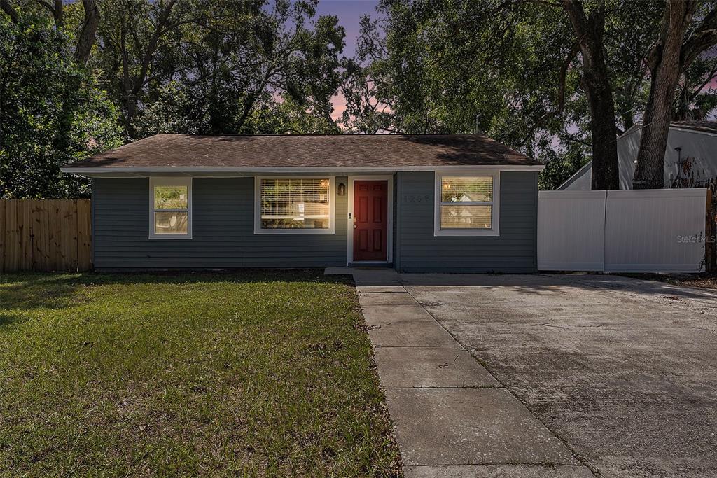 A gray single-story house with a red front door and a concrete driveway — 1209 E FLORA STREET, TAMPA, FL