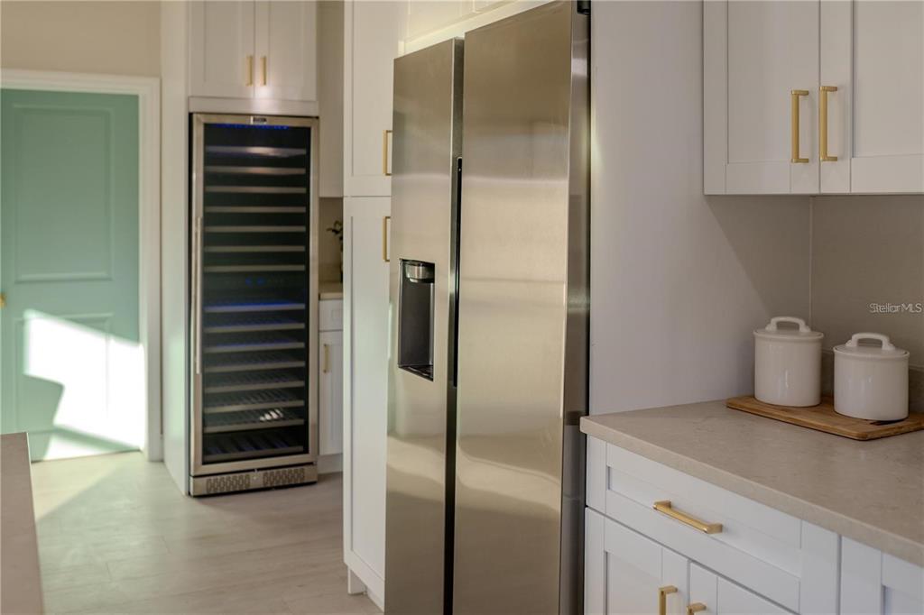 A kitchen features white cabinets, a stainless steel refrigerator, and a tall wine cooler — 5516 GOLDEN DRIVE, TAMPA, FL