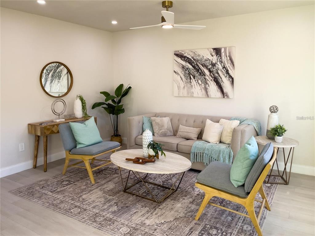 A living room features a beige sofa, two grey armchairs, a coffee table, and area rug — 5516 GOLDEN DRIVE, TAMPA, FL