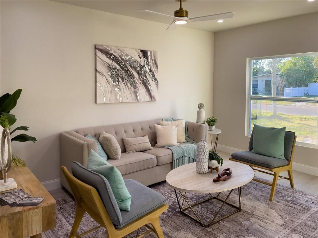 A living room features a beige sofa, two gray chairs, a coffee table, and artwork — 5516 GOLDEN DRIVE, TAMPA, FL