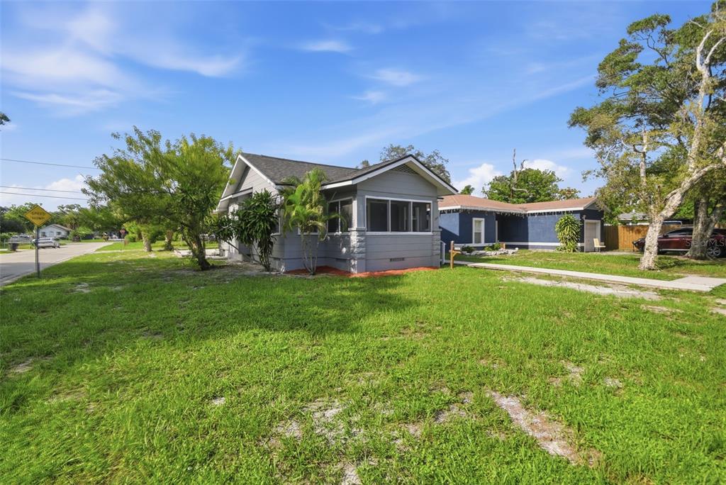 A gray house with a screened front porch sits on a grassy lot with trees — 3745 S 16TH AVENUE S, ST PETERSBURG, FL