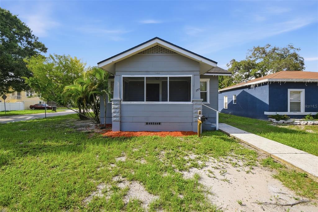 A gray bungalow with a screened front porch and a concrete walkway sits on a lawn — 3745 S 16TH AVENUE S, ST PETERSBURG, FL