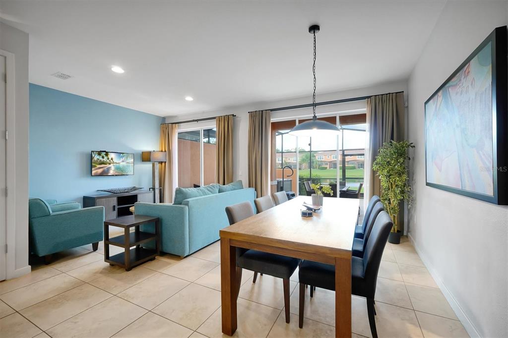 A dining area and living room with tile floors, blue accent walls, and sliding glass doors — 2622 BUGATTI COURT, KISSIMMEE, FL