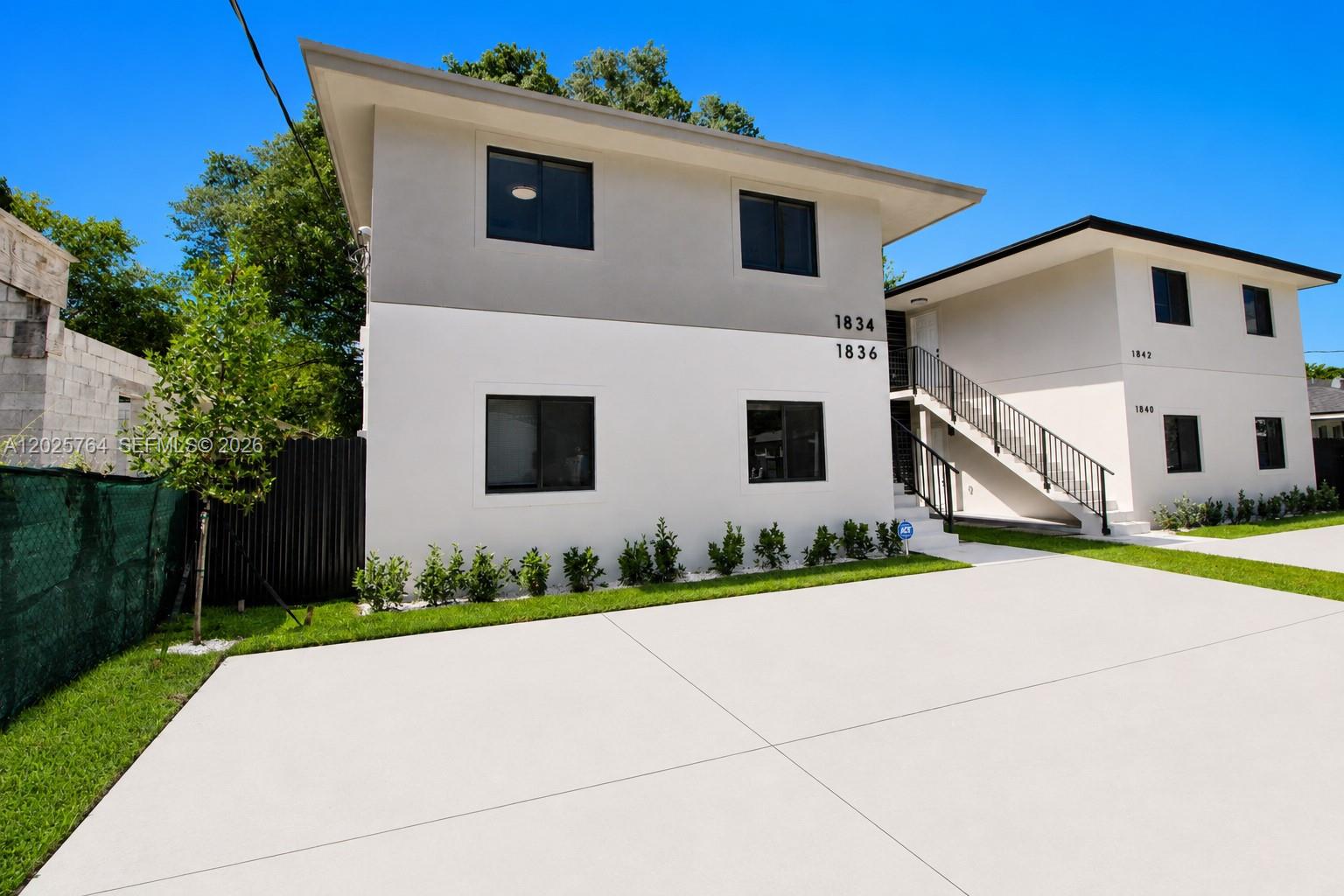 A two-story apartment building with white stucco walls, black-framed windows, and an exterior staircase — 1836 NW 63rd St # 1836, Miami FL 33147, MIAMI, FL