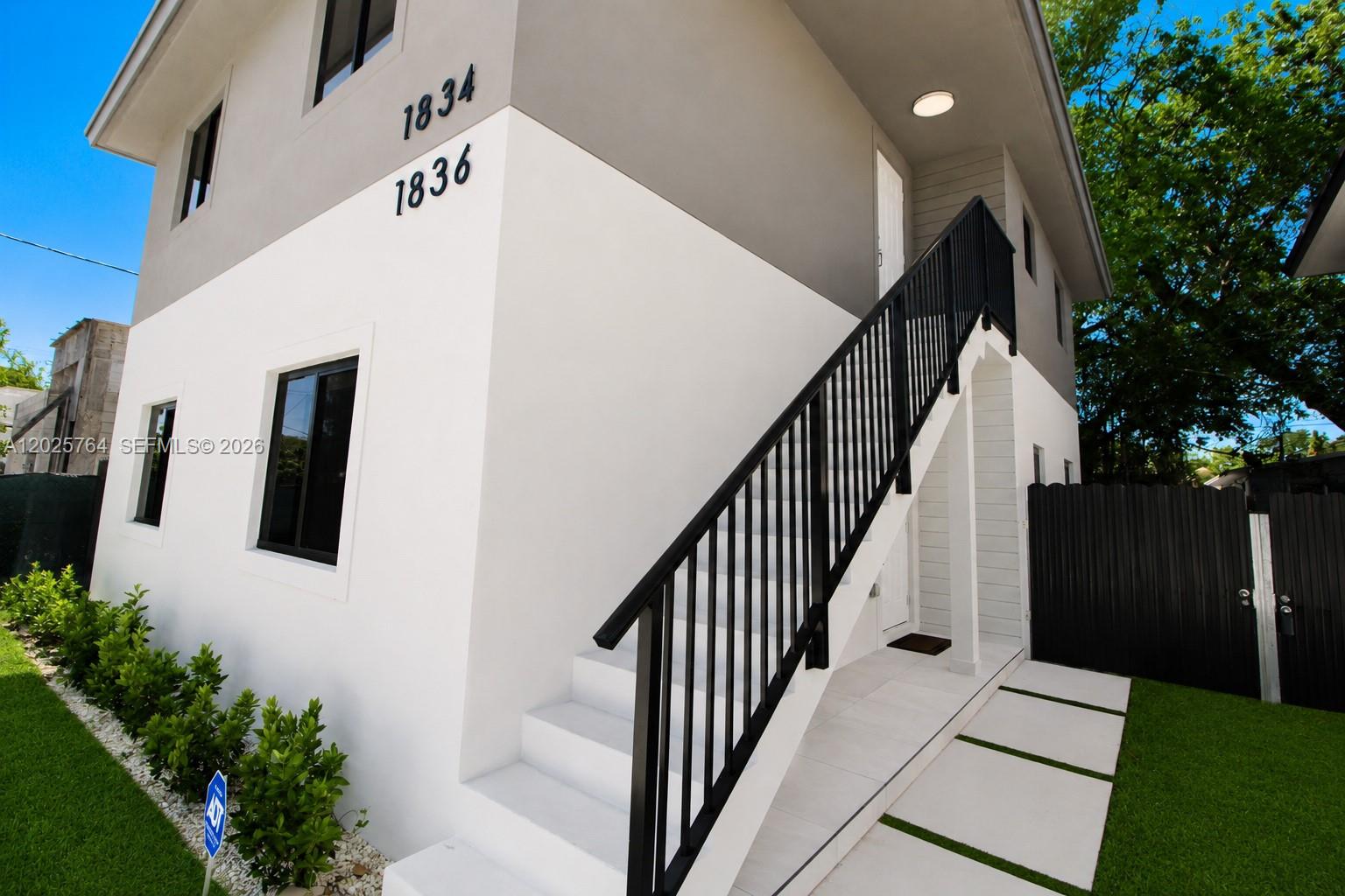 A two-story building exterior features white walls, black railings, and an outdoor staircase — 1836 NW 63rd St # 1836, Miami FL 33147, MIAMI, FL