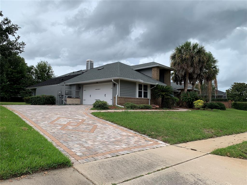 A gray house with a paver driveway and a two-car garage under a cloudy sky — 434 SILVER DEW STREET, LAKE MARY, FL