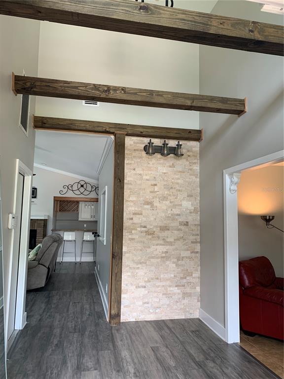 A hallway features a stone accent wall, exposed wooden beams, and gray wood-look flooring — 434 SILVER DEW STREET, LAKE MARY, FL