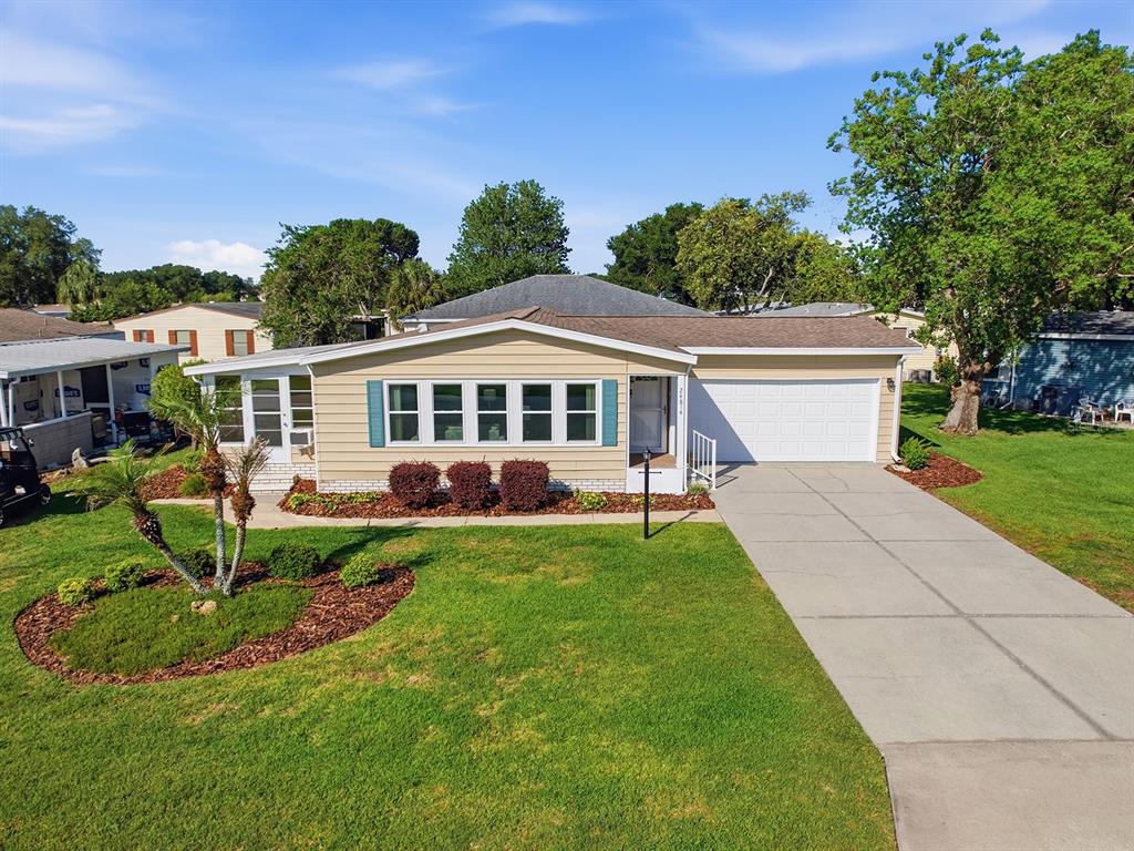 An exterior view of a single-story tan house with a garage and a front lawn — 24814 PINE HL, LEESBURG, FL