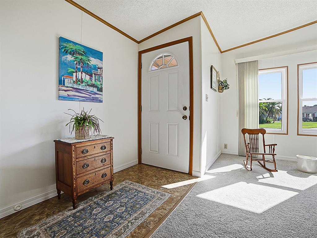 An entryway features a wooden chest, a rocking chair, and a white front door — 24814 PINE HL, LEESBURG, FL