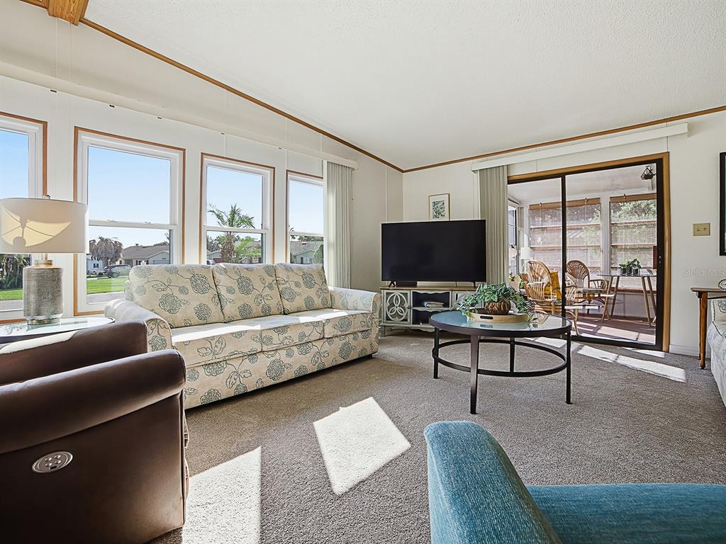 A living room features a floral sofa, a round coffee table, and a sliding glass door — 24814 PINE HL, LEESBURG, FL