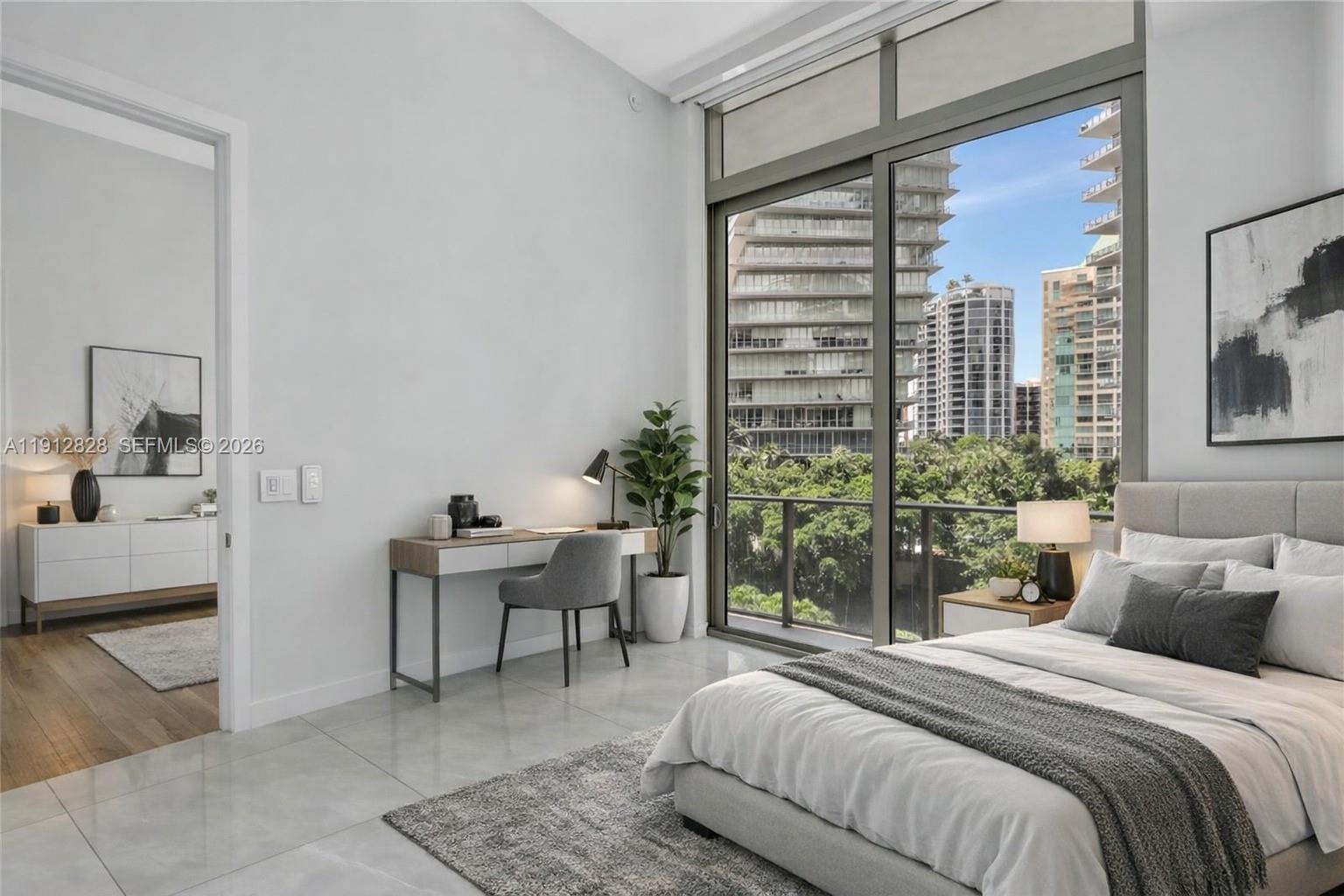 A modern bedroom features a desk, a bed, and floor-to-ceiling windows overlooking city buildings — 2655 S Bayshore Dr # 405, Miami FL 33133, MIAMI, FL