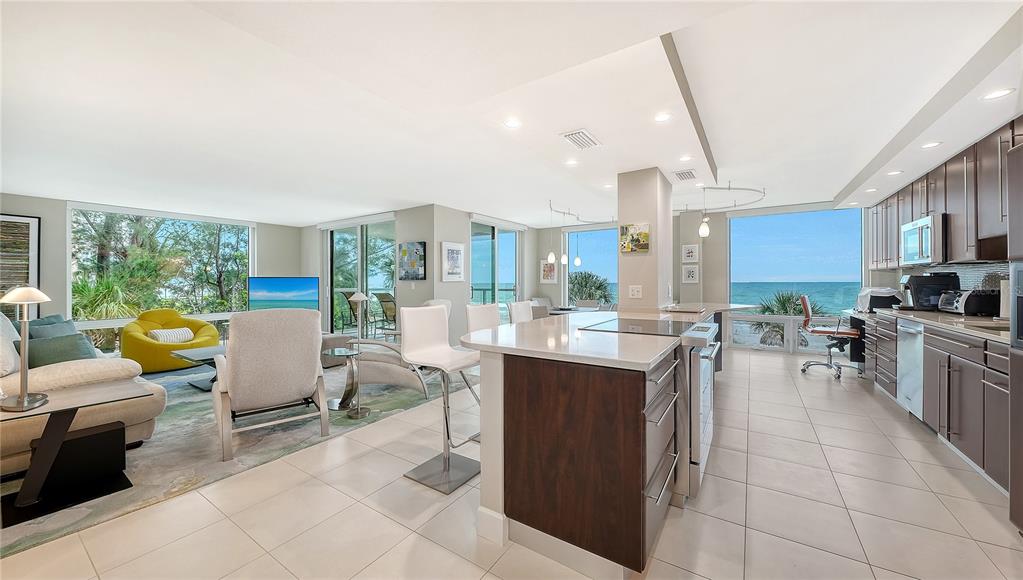 An open-concept kitchen and living area with ocean views, white tile floors, and dark cabinetry — 2425 GULF OF MEXICO DRIVE UNIT 3A, LONGBOAT KEY, FL