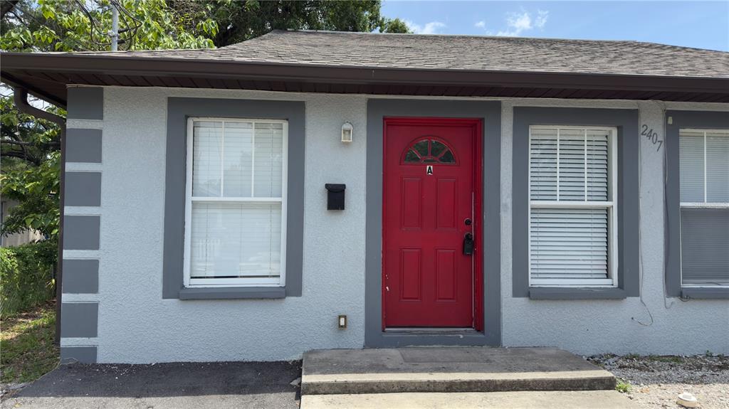 A single-story building exterior features a red front door labeled A and two windows — 2407 E 17TH AVENUE UNIT A, TAMPA, FL