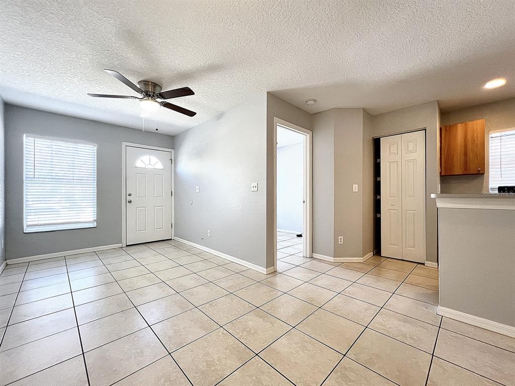 An interior view shows a tiled living area with a ceiling fan and front door — 2407 E 17TH AVENUE UNIT A, TAMPA, FL