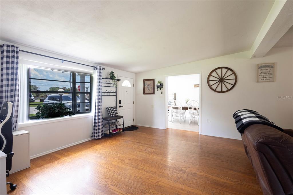 A living room with hardwood floors, a large window, and a doorway leading to a dining area — 2095 W HARTRIDGE TERRACE, WINTER HAVEN, FL