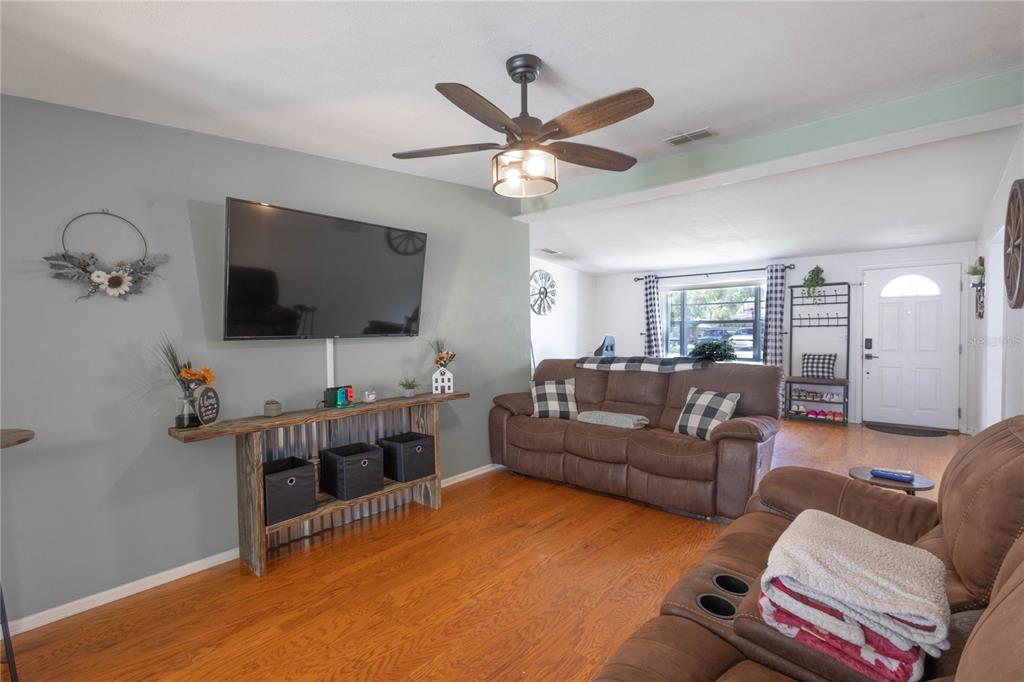 A living room features a wall-mounted television, a wooden console table, and brown leather furniture — 2095 W HARTRIDGE TERRACE, WINTER HAVEN, FL
