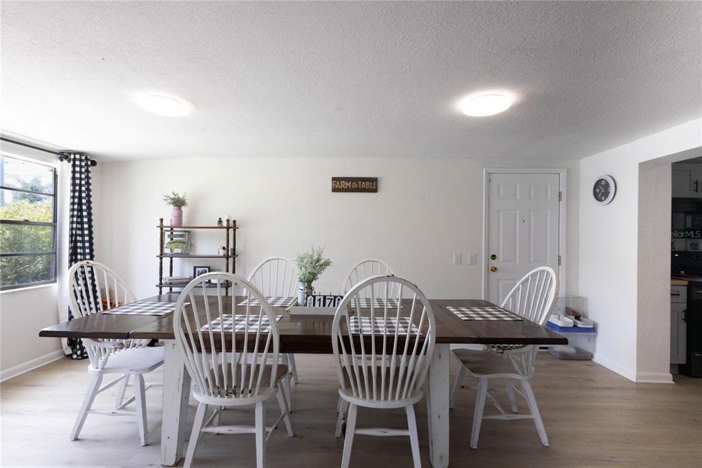 A dining room features a wooden table with white spindle chairs and light wood flooring — 2095 W HARTRIDGE TERRACE, WINTER HAVEN, FL