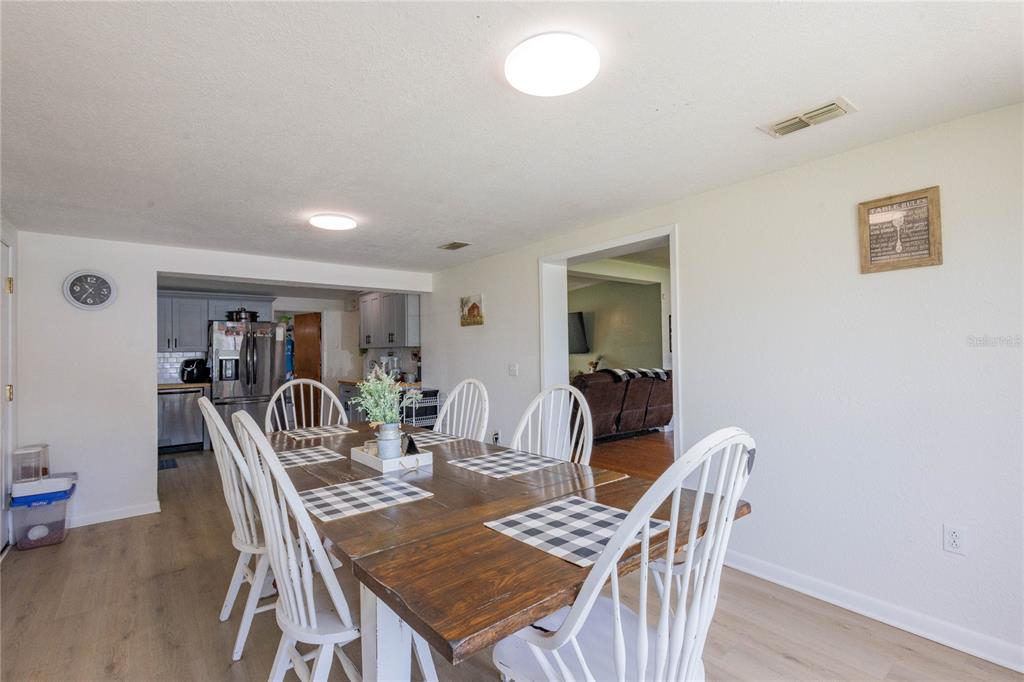 A dining room features a wooden table with white chairs and a view into the kitchen — 2095 W HARTRIDGE TERRACE, WINTER HAVEN, FL