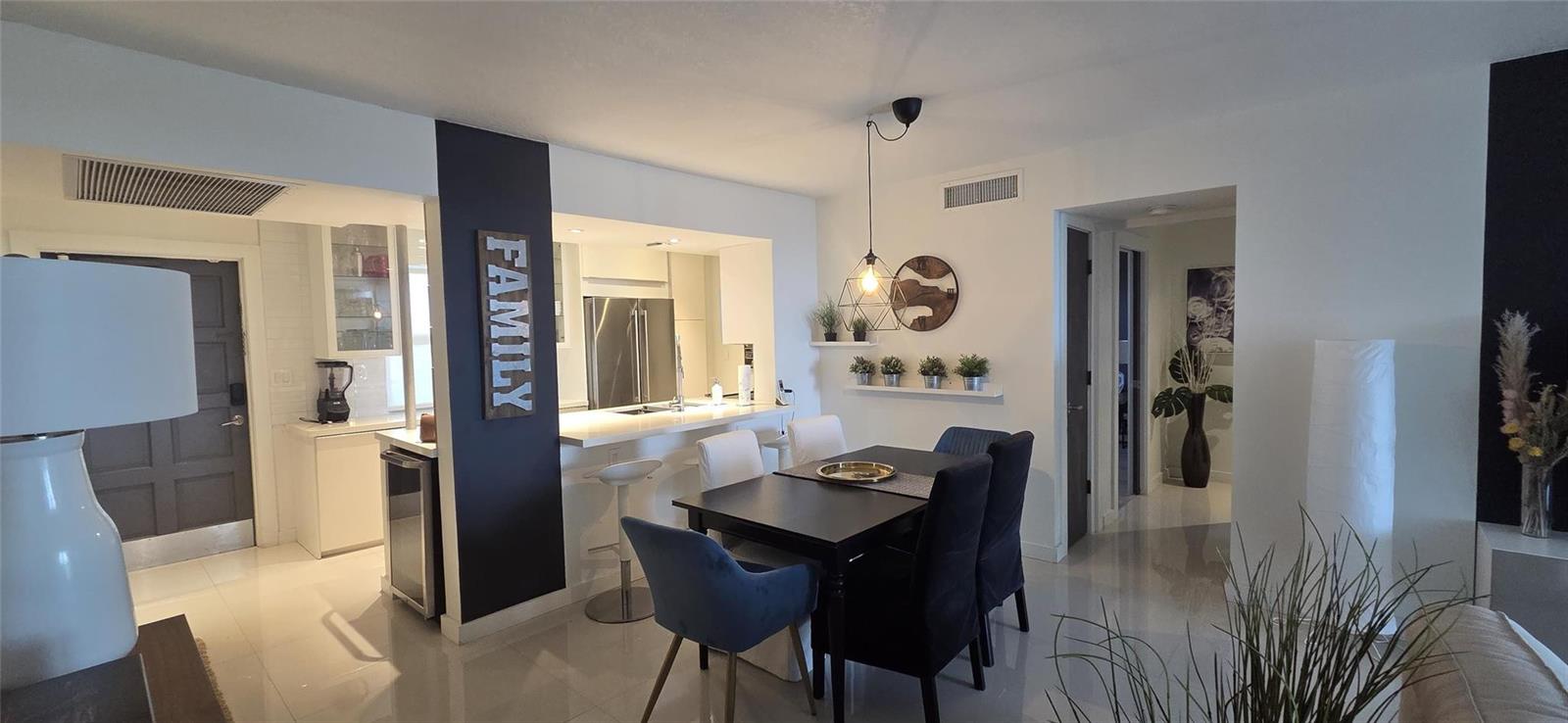 A dining area with a dark table and chairs sits adjacent to a kitchen counter — 2671 S Course Drive # 806, Pompano Beach FL 33069, POMPANO BEACH, FL