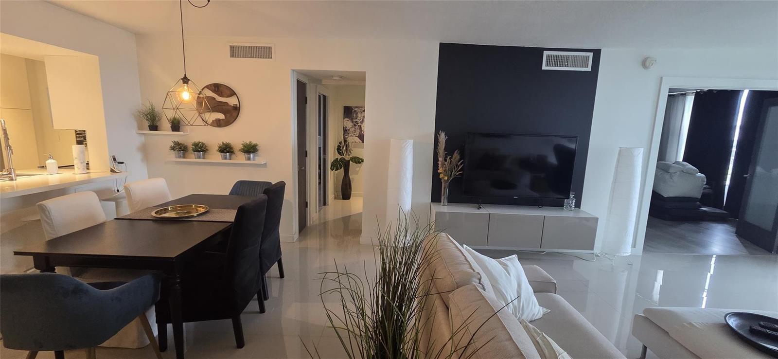 This living and dining area features white tile floors, a dark accent wall, and furniture — 2671 S Course Drive # 806, Pompano Beach FL 33069, POMPANO BEACH, FL
