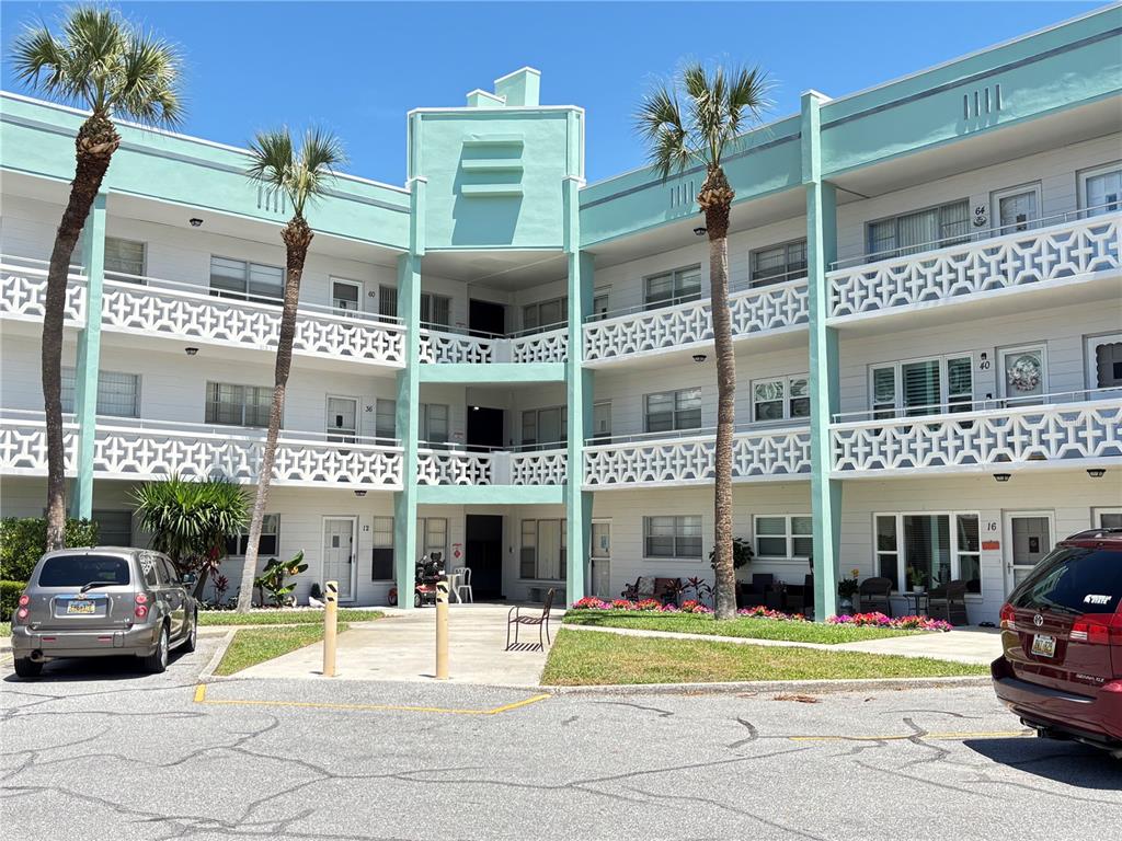 A three-story apartment building with teal accents, palm trees, and a parking lot in front — 2456 ECUADORIAN WAY UNIT 42, CLEARWATER, FL