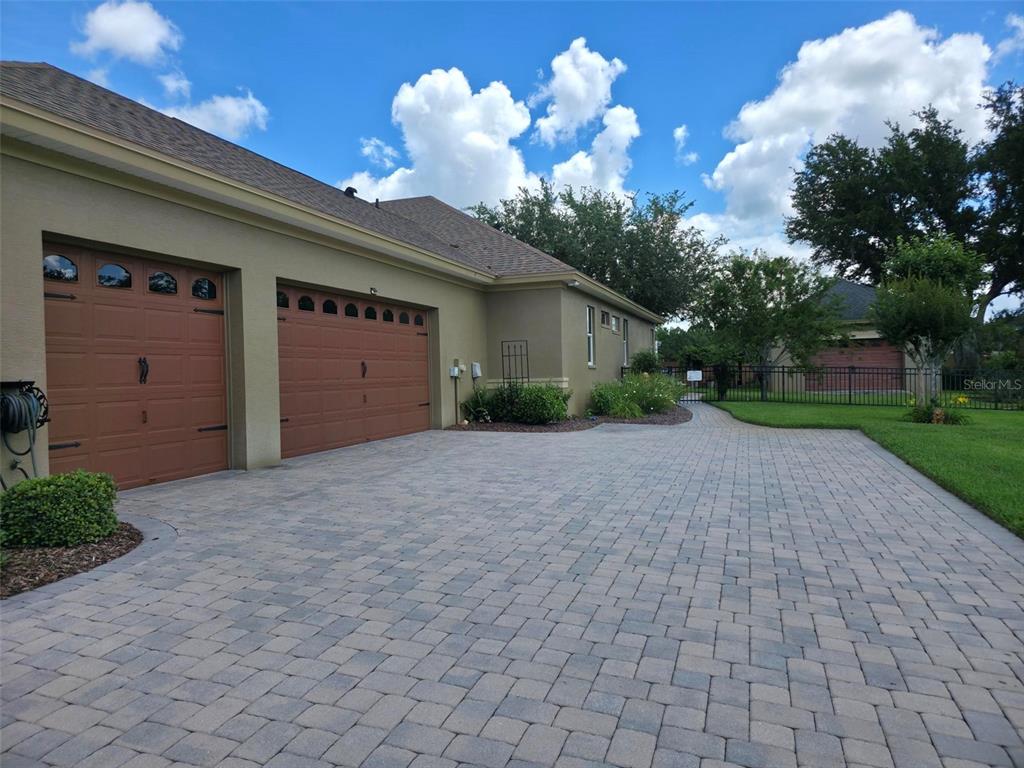 A paved driveway leads to a two-car garage attached to a tan stucco house — 5629 HILLSIDE LANDINGS ROAD, LAKELAND, FL