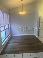 A dining area features dark wood-look flooring, a pendant light, and a large window — 671 OLYMPIC DRIVE UNIT 16-4, OCOEE, FL
