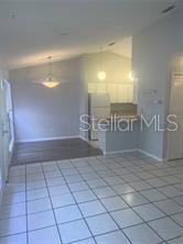 A room with white tile flooring, a dining area with wood floors, and a kitchen — 671 OLYMPIC DRIVE UNIT 16-4, OCOEE, FL