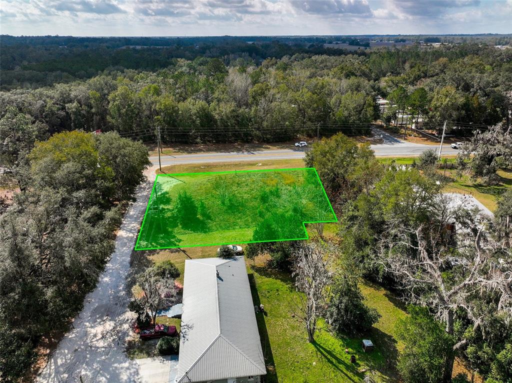 An aerial view shows a vacant, grass-covered lot outlined in green next to a road — 106 NW FAT CAT COURT, LAKE CITY, FL