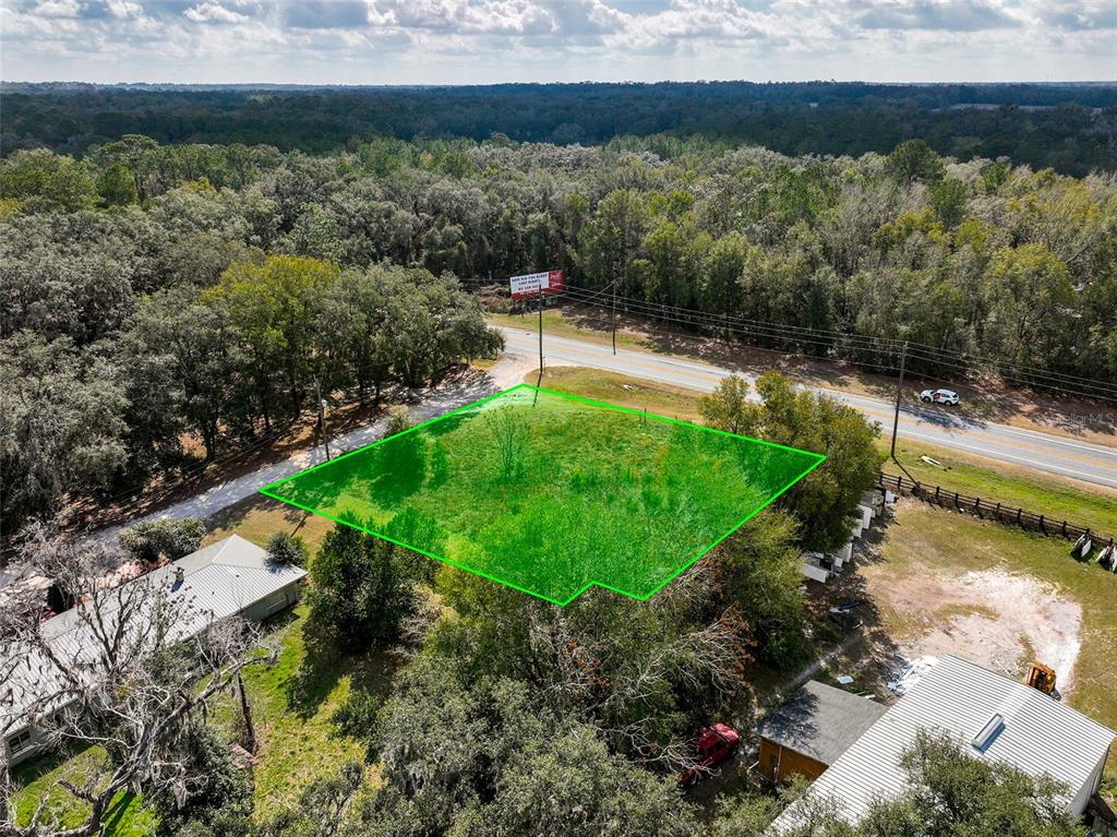 An aerial view shows a vacant, grassy lot outlined in green next to a road — 106 NW FAT CAT COURT, LAKE CITY, FL