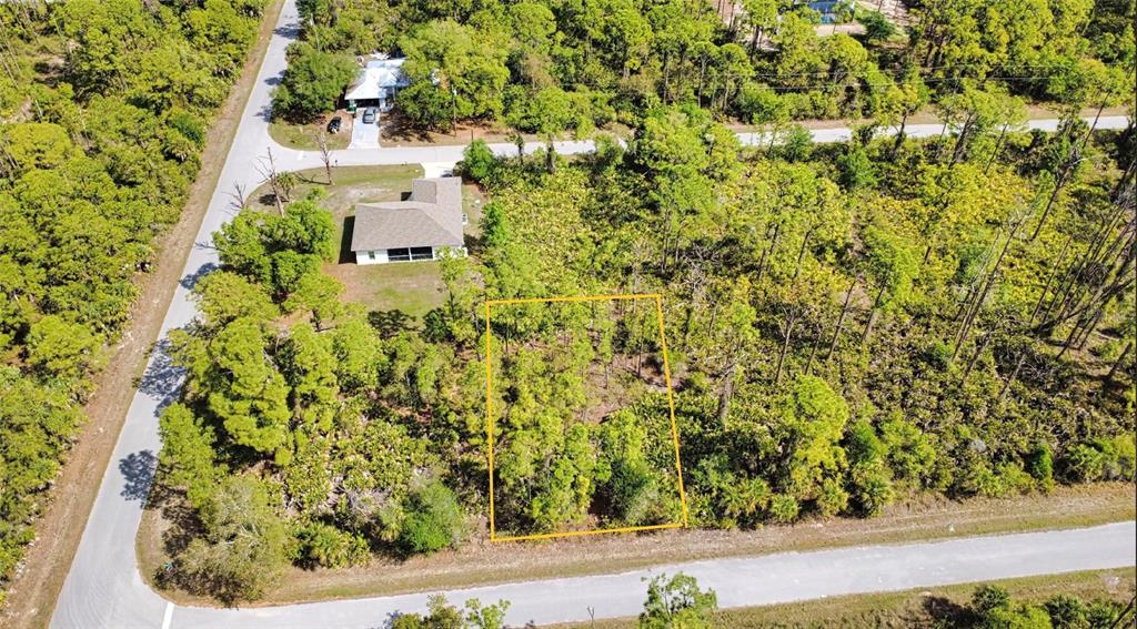 An aerial view shows a rectangular vacant lot outlined in yellow surrounded by wooded land — 13312 HARTH AVENUE, PORT CHARLOTTE, FL