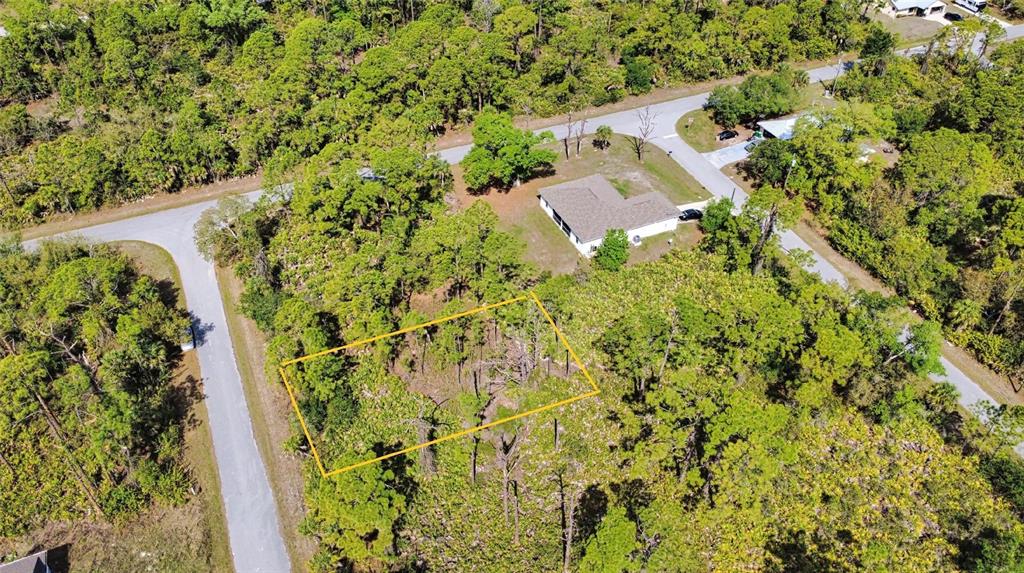 An aerial view shows a rectangular vacant lot outlined in yellow surrounded by dense trees — 13312 HARTH AVENUE, PORT CHARLOTTE, FL