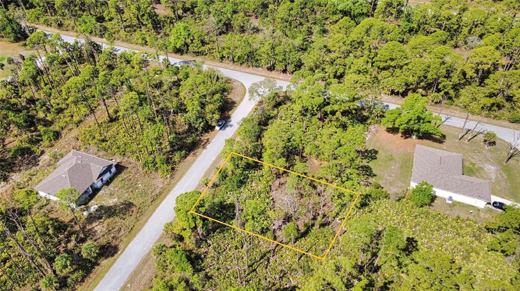 An aerial view shows a vacant, wooded residential lot outlined in yellow near two houses — 13312 HARTH AVENUE, PORT CHARLOTTE, FL