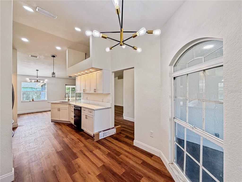 A kitchen with white cabinets, wood-look flooring, and a modern sputnik chandelier — 2617 SUNDANCE CIRCLE, MULBERRY, FL