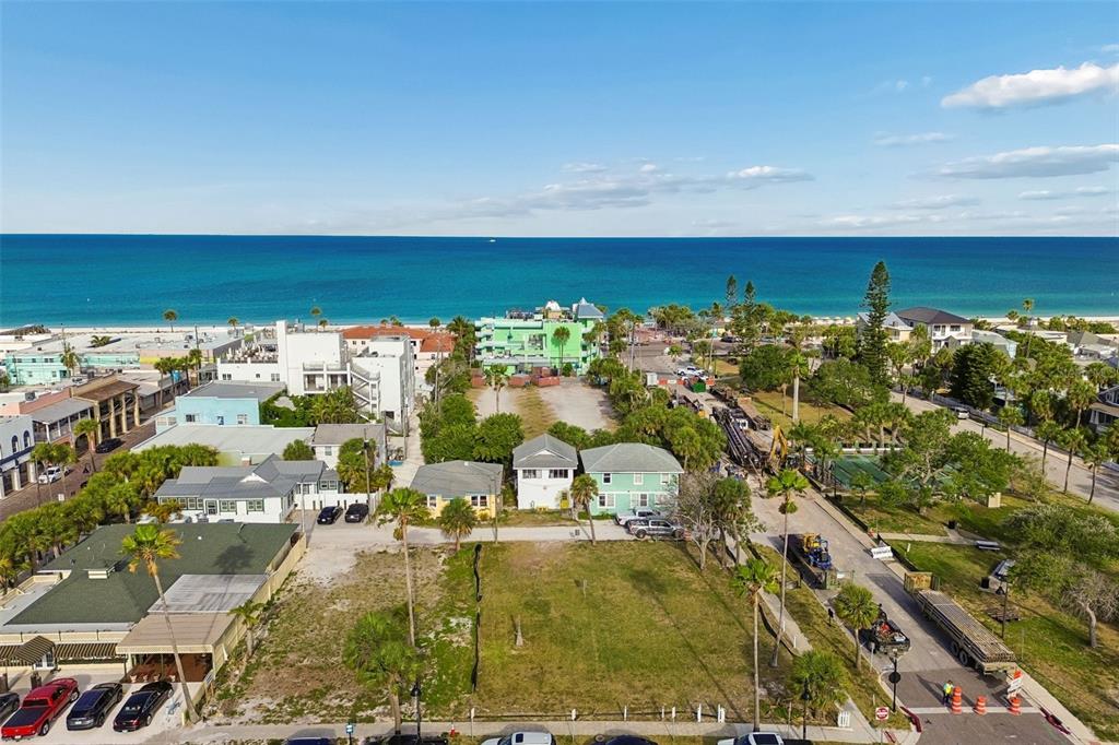 An aerial view shows a vacant grassy lot near a beach with surrounding buildings — 808 PASS A GRILLE WAY, ST PETE BEACH, FL
