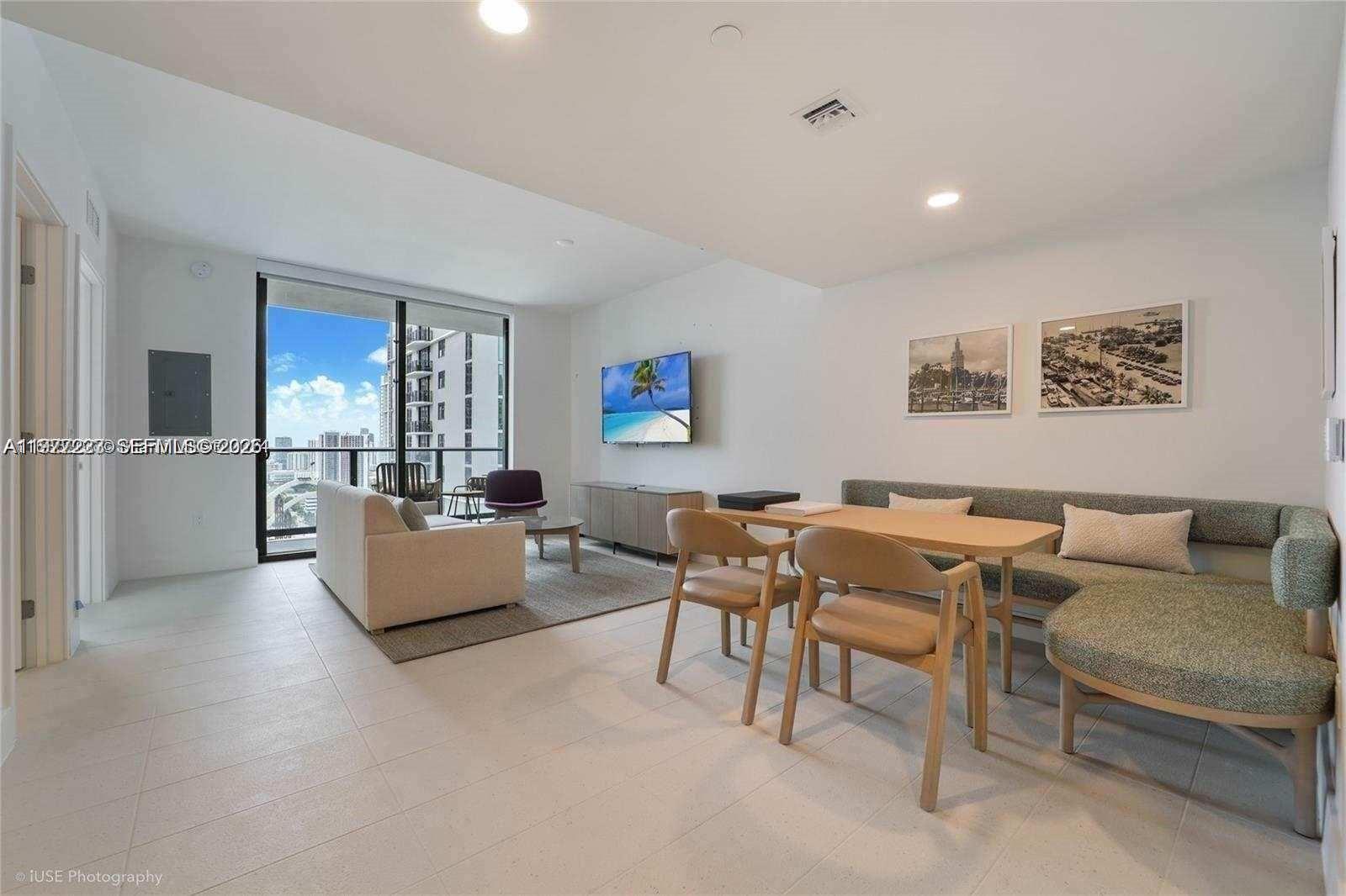A modern living and dining area features tile flooring, a balcony, and neutral furniture — 159 NE 6th St # 4113, Miami FL 33132, MIAMI, FL