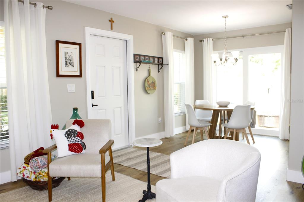 A bright dining area and seating space feature light wood floors, white walls, and furniture — 11861 RAINTREE DRIVE UNIT 65, TAMPA, FL