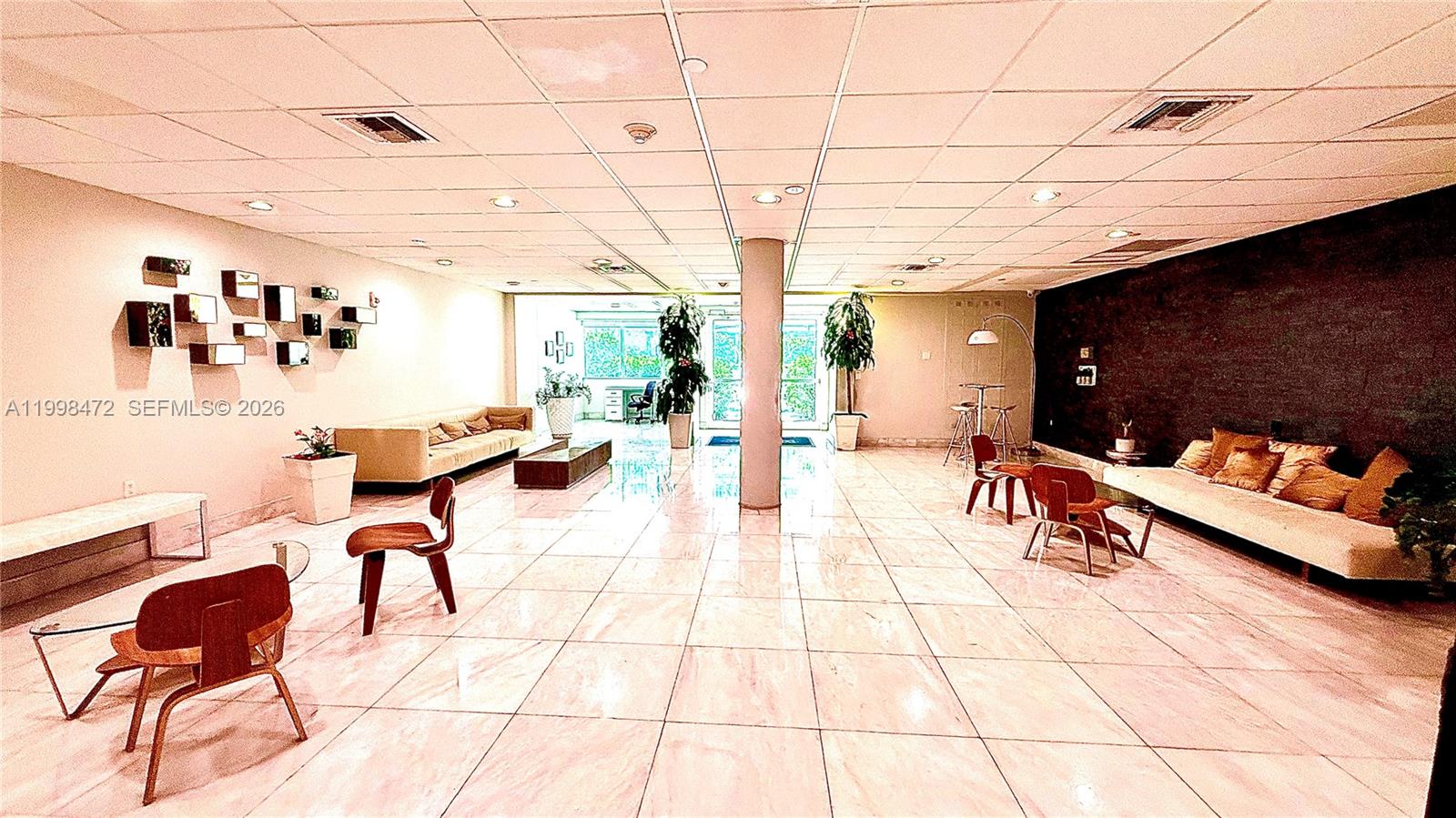 A spacious lobby features light-colored tile flooring, a central support column, and modern seating areas — 1035 West Ave # 306, Miami Beach FL 33139, MIAMI BEACH, FL