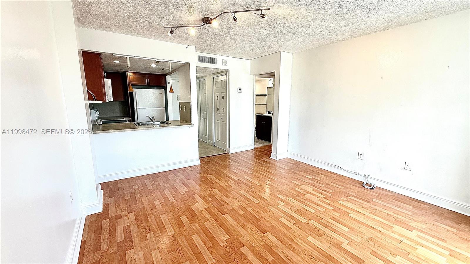 An interior view shows a living area with wood-look flooring, a kitchen pass-through, and track lighting — 1035 West Ave # 306, Miami Beach FL 33139, MIAMI BEACH, FL
