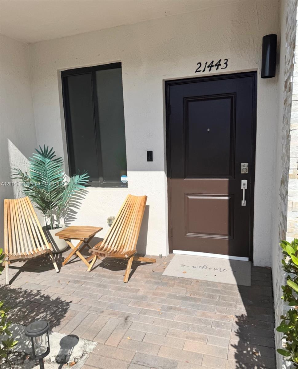 A front entryway features a dark brown door, two wooden chairs, and a small table — 21443 NE 2nd Path # 21443, Miami FL 33179, MIAMI, FL