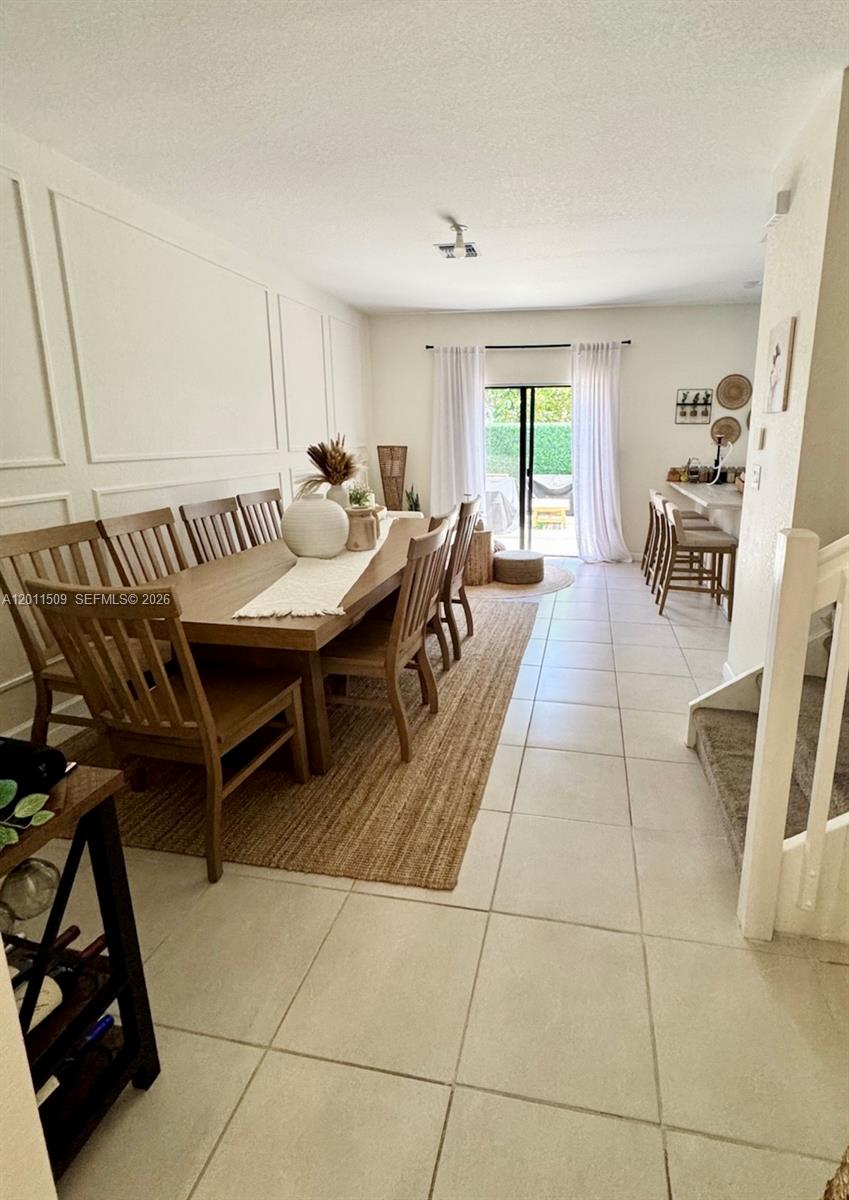 A dining room features a long wooden table, a jute rug, and a breakfast bar — 21443 NE 2nd Path # 21443, Miami FL 33179, MIAMI, FL