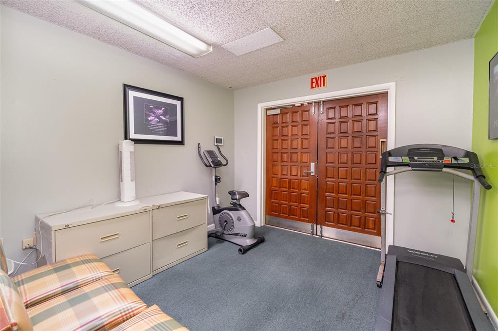 A room with a treadmill, stationary bike, filing cabinet, and double doors marked with an exit sign — 6005 SILVER STAR ROAD, ORLANDO, FL